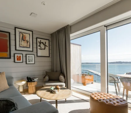 Vardagsrum i hotellsvit på Slottsholmen med stora fönster och balkong med havsutsikt.