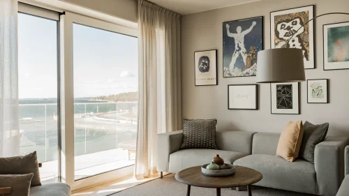 Vardagsrum i hotellsvit med två soffor, bord och stora fönster med utsikt över havet.