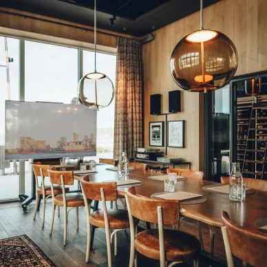 Konferensrum med långbord, stolar, modern teknik och stora fönster med utsikt över vattnet.