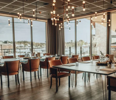 Modern konferenslokal på Slottsholmen med stora fönster, havsutsikt, eleganta lampor och bekväma stolar.