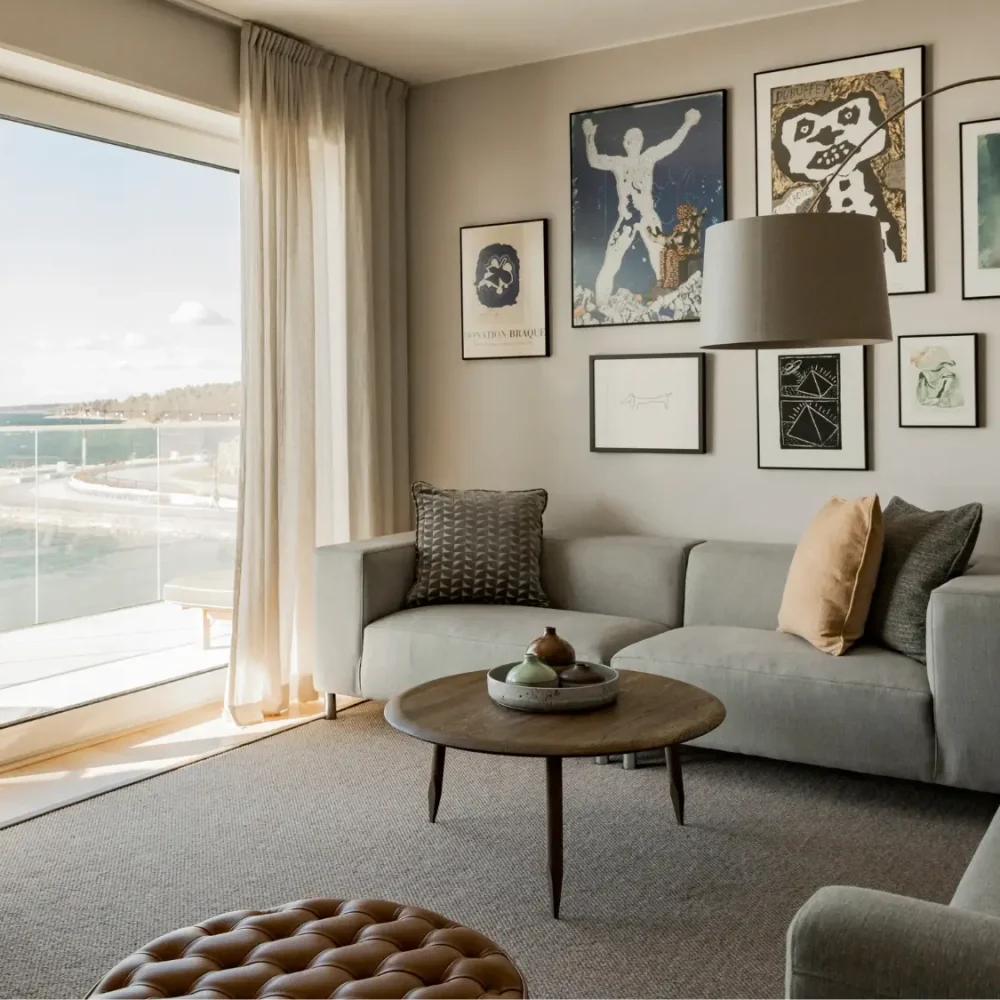Vardagsrum i svit på med soffor, konst på väggarna, stora fönster och balkong med sjöutsikt.