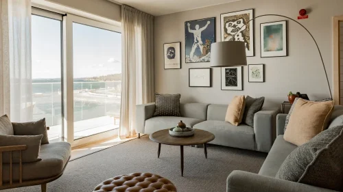 Vardagsrum i svit på med soffor, konst på väggarna, stora fönster och balkong med sjöutsikt.