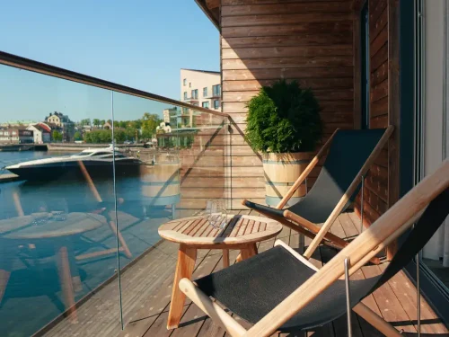 Balkong med två solstolar och ett litet bord på Slottsholmens flytande hotellrum, med utsikt över vattnet.